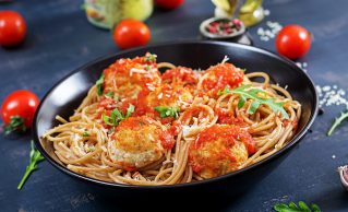 Italian pasta. Spaghetti with meatballs and parmesan cheese in black plate on dark rustic wood background.  Dinner. Slow food concept